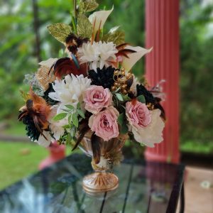 High end floral decor with a gold glass and mixed flowers featuring pink and white roses in an elegant vase.