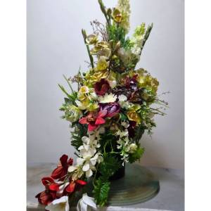 Cascading silk flower arrangement on a black pedestal with a matching ground floral piece and three lit candles for an event in Melbourne.