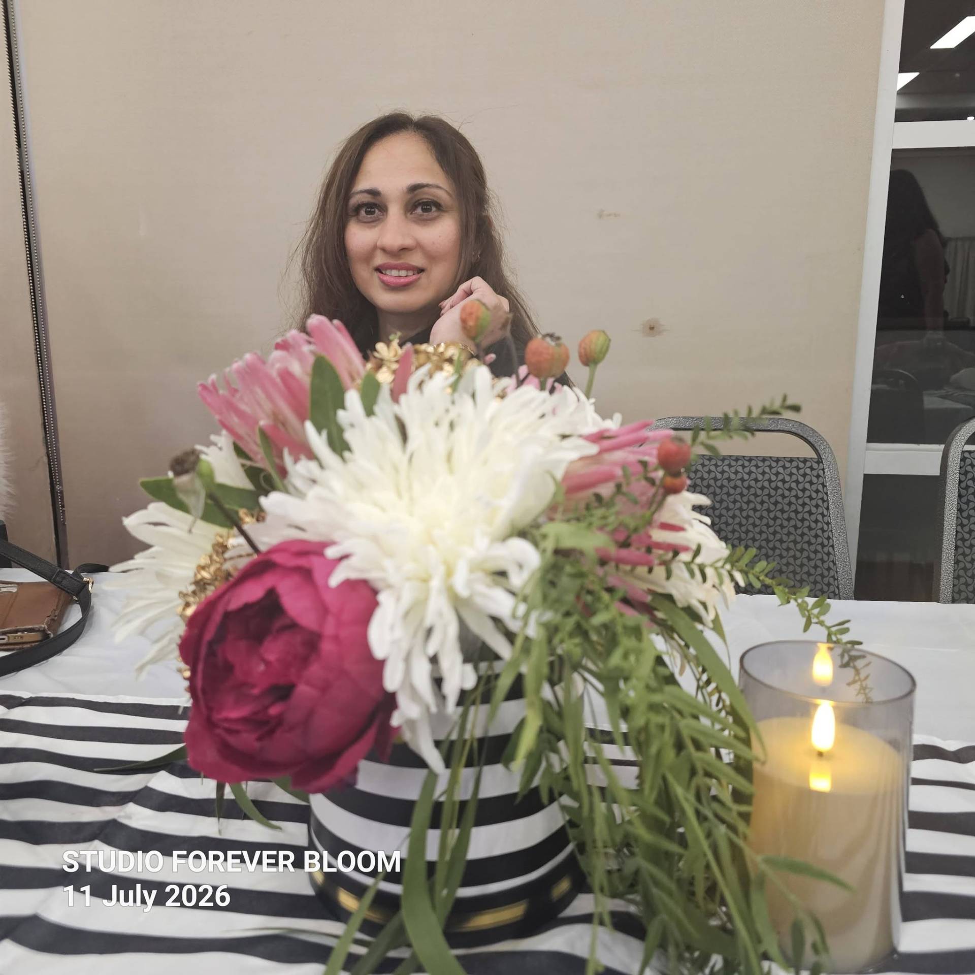 A group of four smiling elegantly dressed women standing behind a Studio Forever Bloom black and white striped hybrid floral centerpiece during an event on 11 July 2026 , Silk Floral Event Decor Melbourne