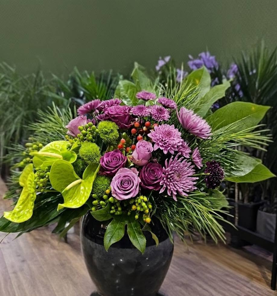 A luxury event decor showcase by Studio Forever Bloom featuring a tall purple and green hybrid floral pillar next to matching silk centerpieces in black pots.