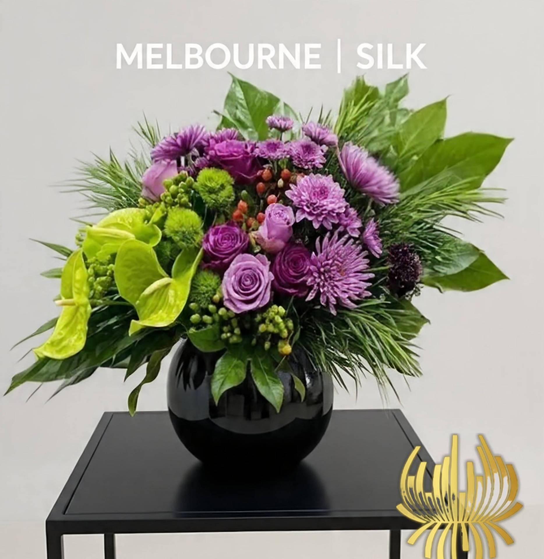 A luxury event decor showcase by Studio Forever Bloom featuring a tall purple and green hybrid floral pillar next to matching silk centerpieces in black pots.