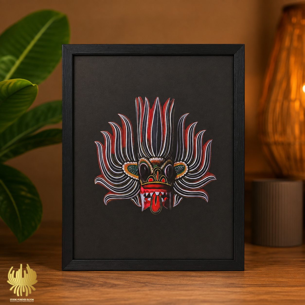 Framed 50x70 cm Traditional Sri Lankan Mask Art featuring intricate red and white patterns on a black background displayed on a wooden surface.