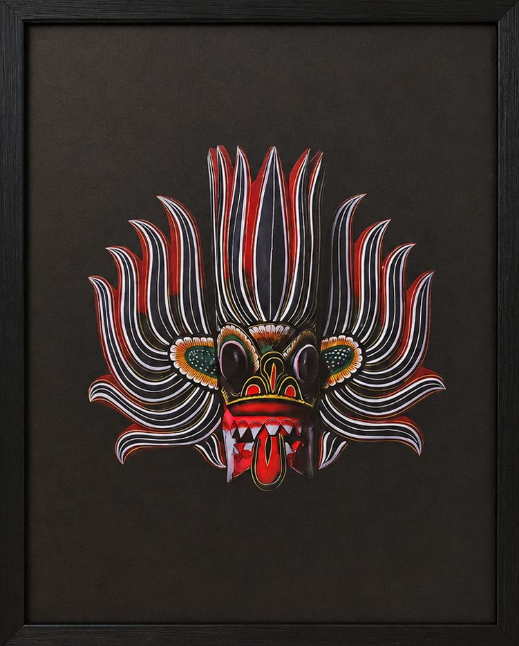 Framed 50x70 cm Traditional Sri Lankan Mask Art featuring intricate red and white patterns on a black background displayed on a wooden surface.