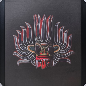 Framed 50x70 cm Traditional Sri Lankan Mask Art featuring intricate red and white patterns on a black background displayed on a wooden surface.